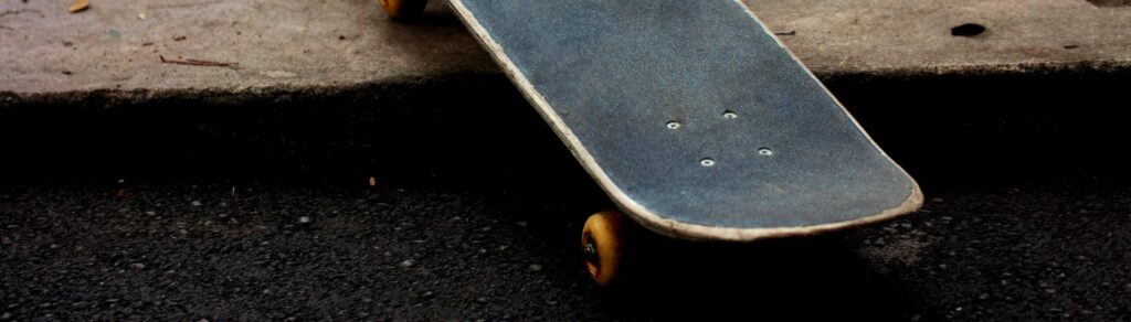 Close-up of a skateboard left on the pavement in an urban street setting.
